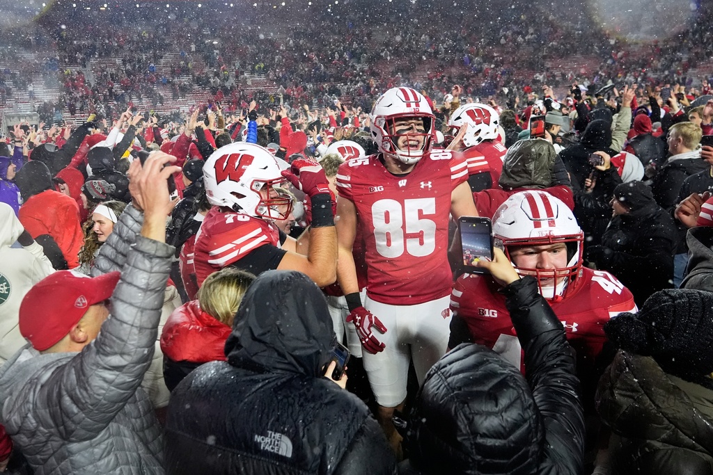 Wisconsin players celebrate as fans storm the field after an NCAA college football game against Washington Saturday, Nov. 8, 2025, in Madison, Wis. (AP Photo/Morry Gash)