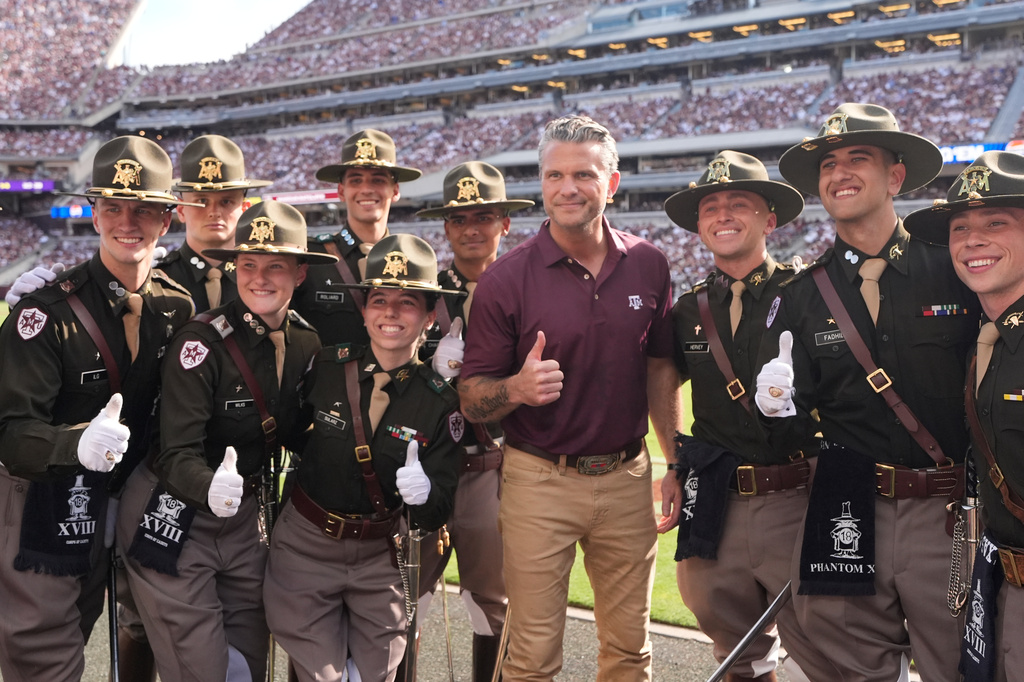 U.S. Secretary of Defense Pete Hegseth, center, poses with members of the Texas A&M Corps of Cadets on the sideline during the second half of an NCAA college football game against Kentucky, Saturday, Sept. 19, 2026, in College Station, Texas. (AP Photo/David J. Phillip)