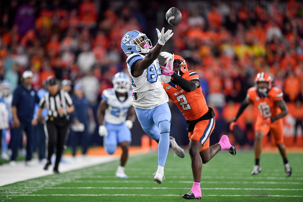 North Carolina tight end Shamar Easter, center left, reaches for a pass that fell incomplete as he is defended by Syracuse defensive back Duce Chestnut (2) during the first half of an NCAA college football game Friday, Oct. 31, 2025, in Syracuse, N.Y. (AP Photo/Adrian Kraus)