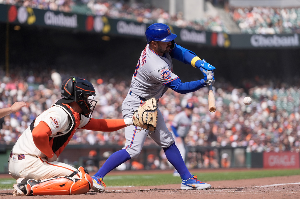 New York Mets' Luis Torrens, right, hits a two-run double next to San Francisco Giants catcher Patrick Bailey, left, during the eighth inning of a baseball game in San Francisco, Sunday, April 5, 2026. (AP Photo/Jeff Chiu)