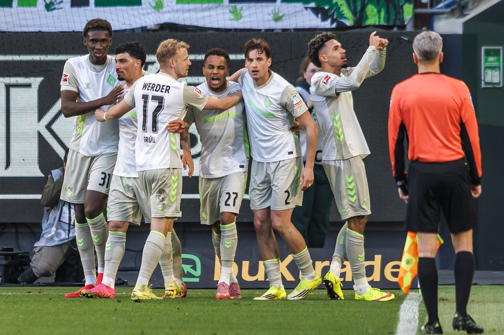 Bremen's Justin Njinmah, right, celebrates after scoring the opening goal during the German Bundesliga soccer match between VfL Wolfsburg and SV Werder Bremen in Wolfsburg, Germany, Saturday, March 21, 2026. (Andreas Gora/dpa via AP)