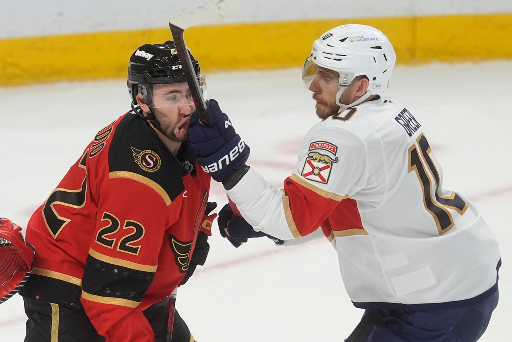 Florida Panthers' A.J. Greer (10) gets his stick up on Ottawa Senators' Michael Amadio (22) during third period NHL action in Ottawa, Ontario, Thursday, April 9, 2026. (Adrian Wyld/The Canadian Press via AP)