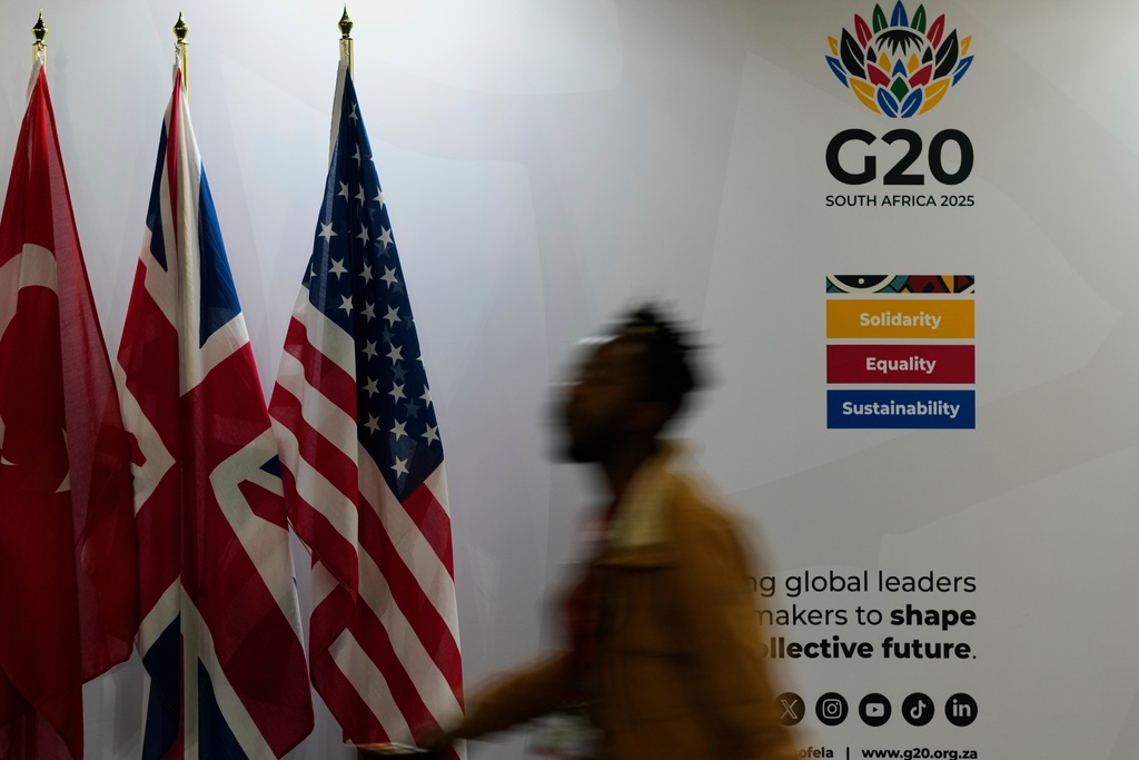 A journalist walks past flags of participating countries at the media centre of the G20 Summit in Johannesburg, South Africa, Friday, Nov. 21, 2025. (AP Photo/Themba Hadebe)