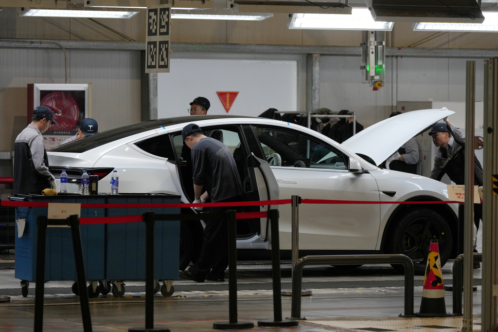 FILE - People work on the Tesla Model Y production line at the Tesla Gigafactory assembly plant during a media organized tour, in Shanghai, China, Tuesday, April 14, 2026. (AP Photo/Andy Wong, File)