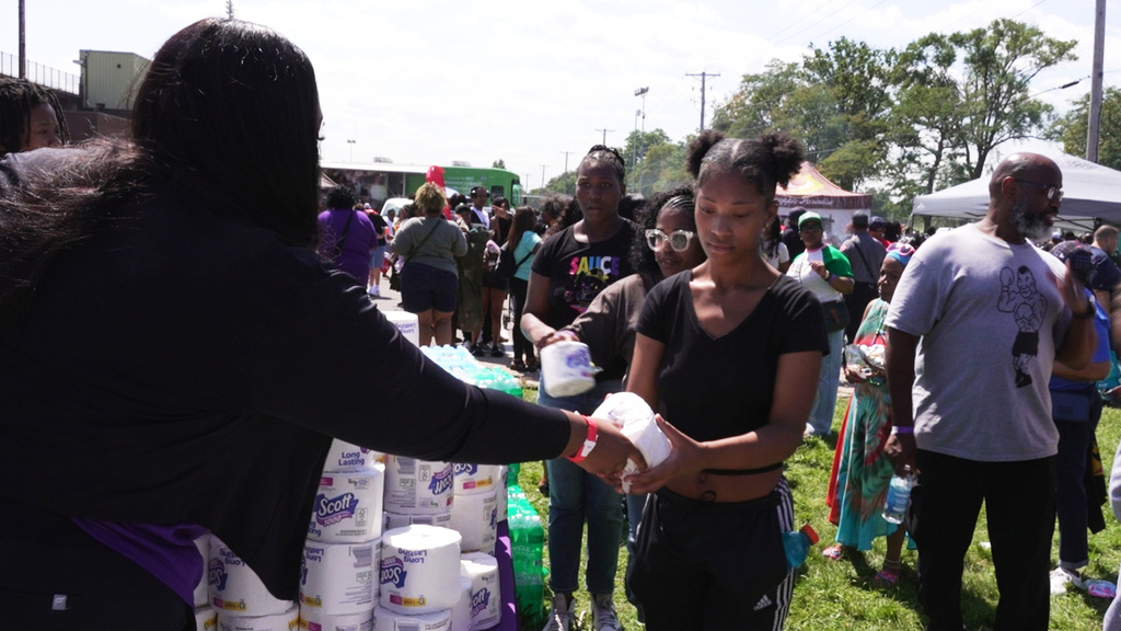 In this photo taken from video, an attendee receives toilet paper from a volunteer at a free community relief event for those struggling after a nearly two-week long power outage in Gary, Ind., Aug. 24, 2026. (AP Photo/Laura Bargfeld)