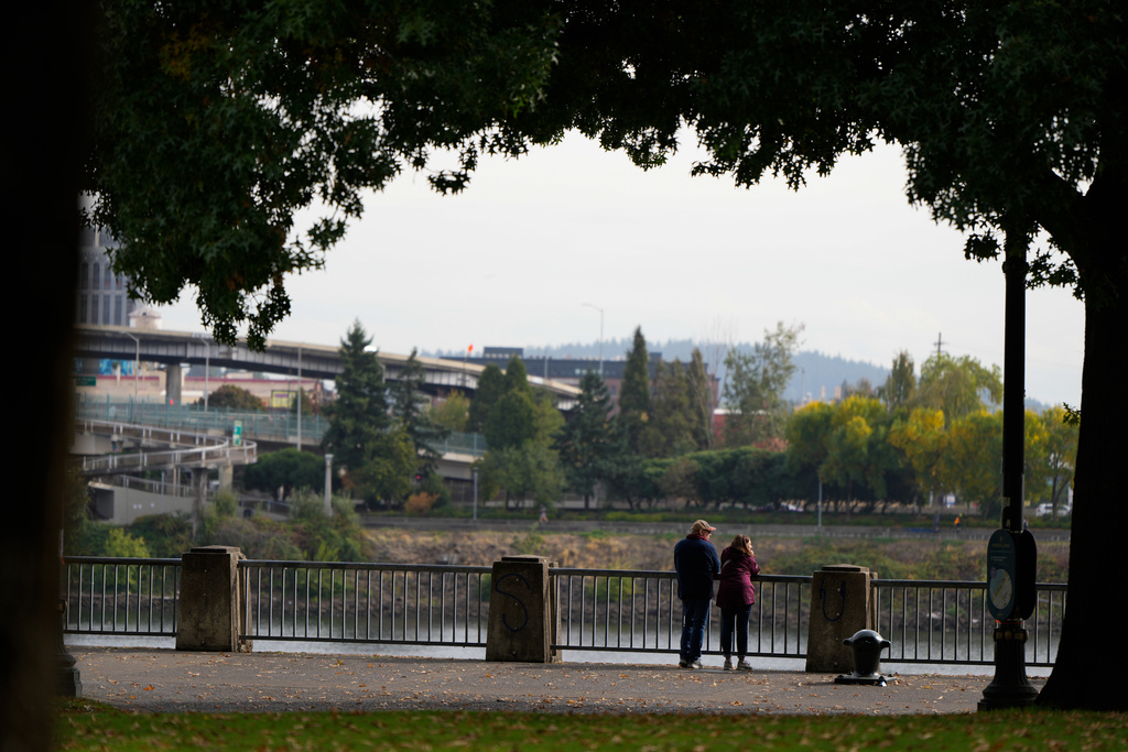People pause to look out at the Willamette River as they walk along Waterfront Park Trail on Thursday, Oct. 9, 2025, in Portland, Ore. (AP Photo/Jenny Kane)