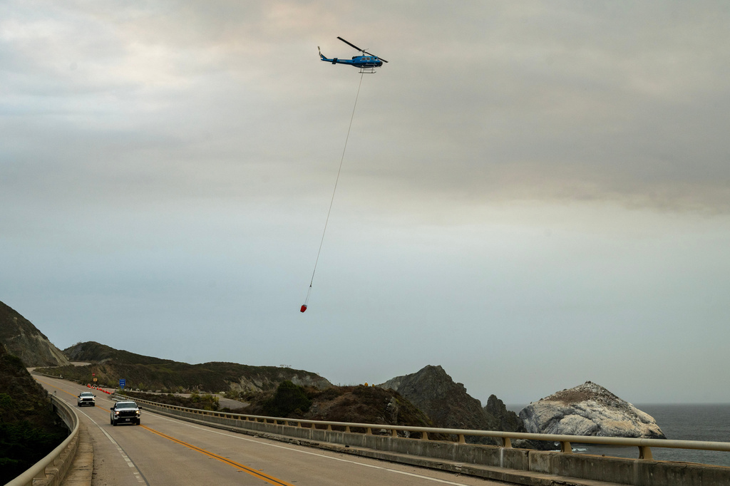 A helicopter flies over Willow Creek to fill up a water bucket to help fight the Plaskett Fire near Big Sur, Calif., Thursday, Aug. 27, 2026. (AP Photo/Nic Coury)