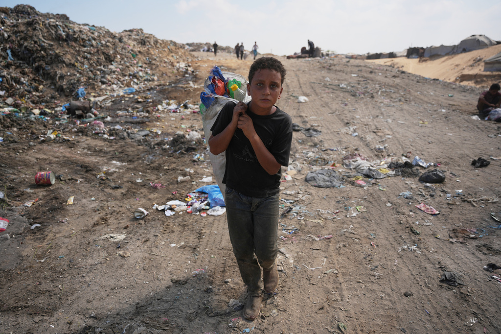 A Palestinian boy leaves a garbage dump after collecting combustible materials to use as fuel for cooking due to a shortage of cooking gas, in Deir al-Balah, central Gaza Strip, Saturday, Aug. 22, 2026. (AP Photo/Abdel Kareem Hana)