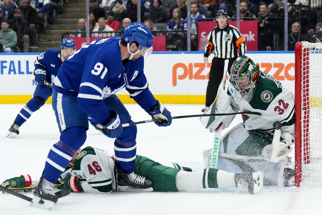 Minnesota Wild goaltender Filip Gustavsson (32) makes a save on Toronto Maple Leafs forward John Tavares (91) during the second period of an NHL hockey game in Toronto, Monday, Jan. 19, 2026. (Nathan Denette/The Canadian Press via AP)