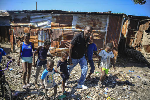 FILE - Jimmy Cherizier, a former elite police officer known as Barbecue who now runs a gang federation, walks hand in hand with children as he visits La Saline district of Port-au-Prince, Haiti, Jan. 24, 2023. Internationally, Cherizier is known as Haiti's most powerful and feared gang leader, sanctioned by the United Nations for &quot;serious human rights abuses,&quot; and the man behind a fuel blockade that brought the Caribbean nation to its knees in late 2022. (AP Photo/Odelyn Joseph, File)