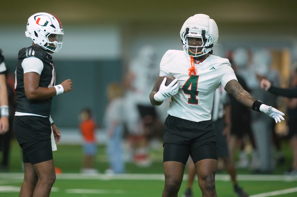 Miami running back Mark Fletcher Jr. (4) gestures to quarterback Darian Mensah during a practice session at their training facility, Tuesday, Aug. 4, 2026, in Coral Gables, Fla. (AP Photo/Marta Lavandier)