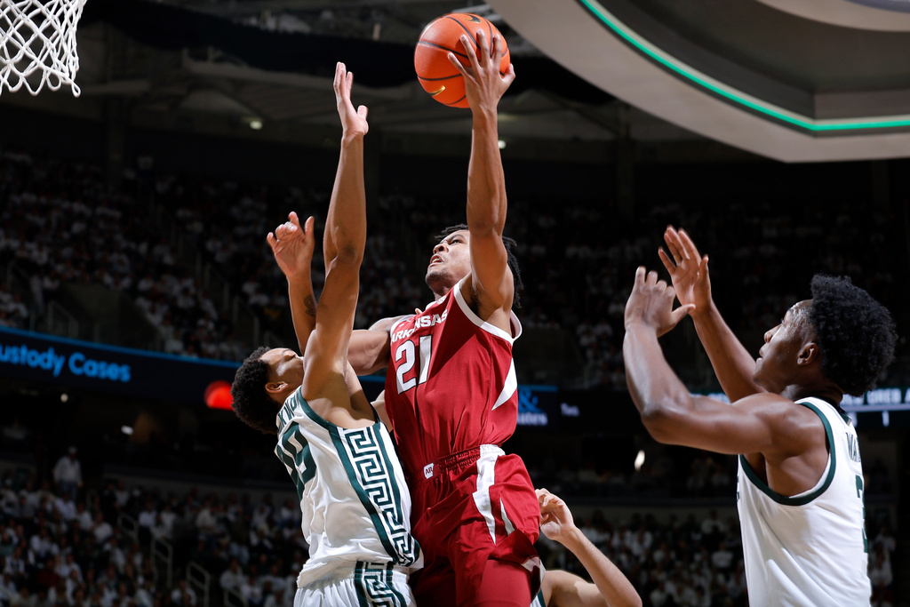 Arkansas guard D.J. Wagner (21) shoots against Michigan State guard Divine Ugochukwu, left, and forward Cam Ward, right, during the first half of an NCAA college basketball game, Saturday, Nov. 8, 2025, in East Lansing, Mich. (AP Photo/Al Goldis)