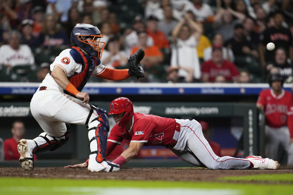 Los Angeles Angels' Logan O'Hoppe (14) scores ahead of a throw to Houston Astros catcher Yainer Diaz, left, during the ninth inning of a baseball game against the Houston Astros in Houston, Saturday, Aug. 30, 2025. (AP Photo/Ashley Landis)