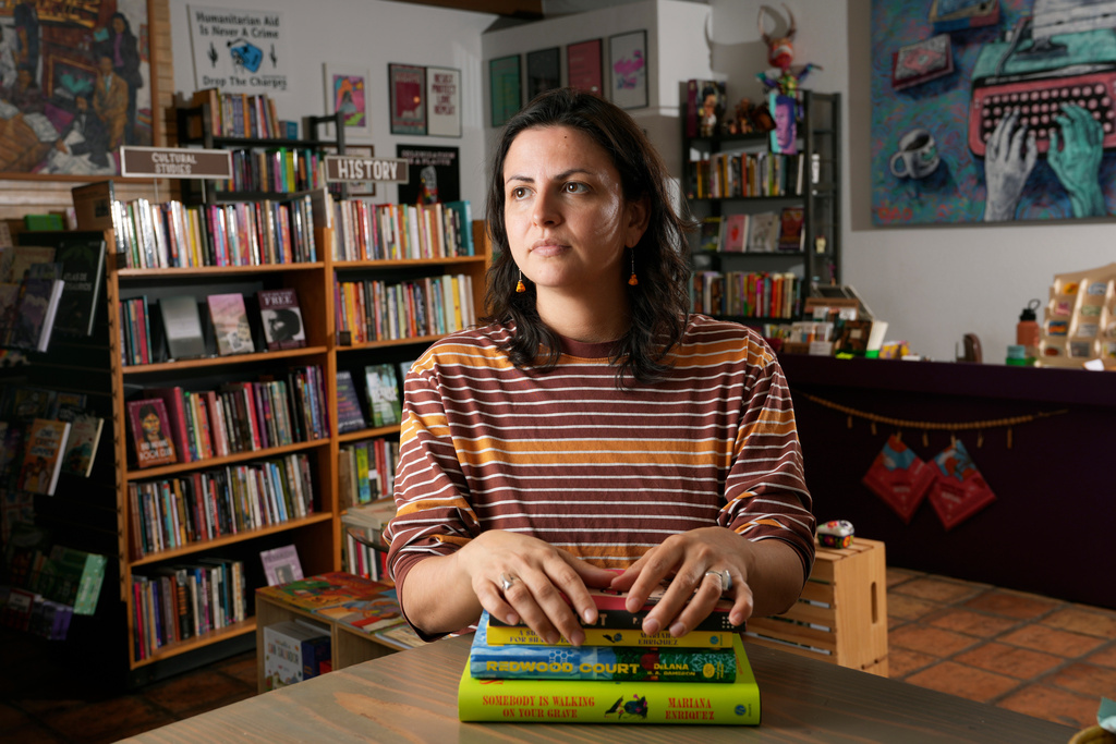 Chawa Magaña, owner of Palabras Bilingual Bookstore, poses with a few of her favorite books Monday, Oct. 6, 2025, in Phoenix. (AP Photo/Ross D. Franklin)