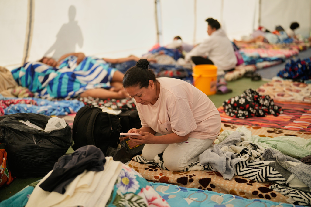 A woman checks her mobile phone at a temporary shelter for people whose homes were damaged after an earthquake struck Pereira, Colombia, Wednesday, Aug. 12, 2026. (AP Photo/Fernando Vergara)