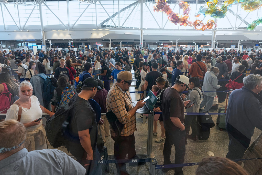 Passengers wait in a security checkpoint line at George Bush Intercontinental Airport Wednesday, March 25, 2026, in Houston. (AP Photo/David J. Phillip)