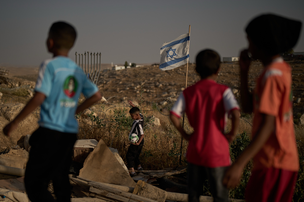 A Palestinian boy retrieves a soccer ball after it landed beyond a barbed-wire fence erected by Israeli settlers next to a football pitch in the West Bank Bedouin village of Umm al-Khair, Tuesday, May 12, 2026. (AP Photo/Leo Correa)