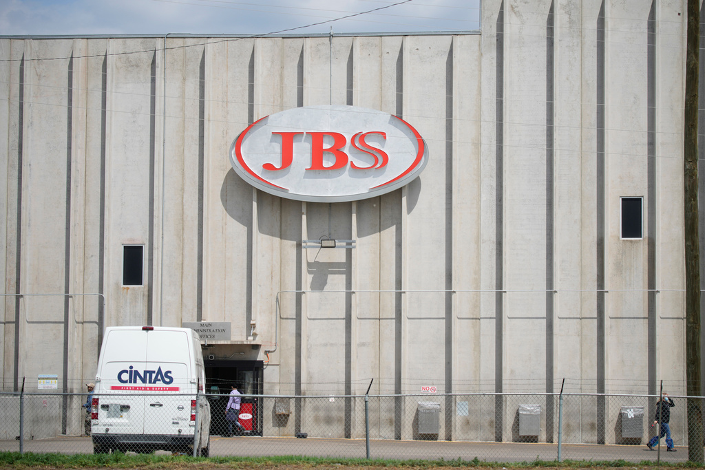 FILE - Employees walk in front of the entrance to the JBS meat processing plant, July 23, 2021, in Greeley, Colo. (AP Photo/David Zalubowski, File)