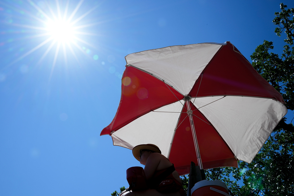 The sun beams down on a lifeguard while she watches over a beach at Lake Harriet during an extreme heat warning, Monday, July 13, 2026, in Minneapolis. (AP Photo/Ellen Schmidt)