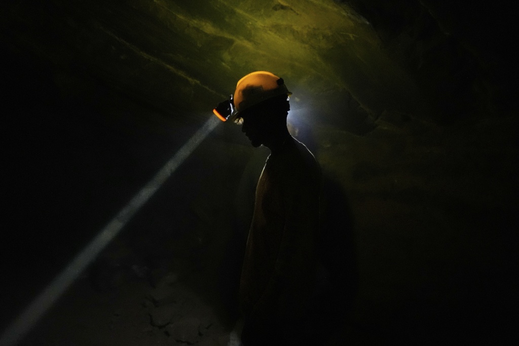 A worker shines his headlamp for colleagues as they emerge from one of the caverns while mining for mercury in San Joaquin, Mexico, Tuesday, Aug. 19, 2025. (AP Photo/Fernando Llano)