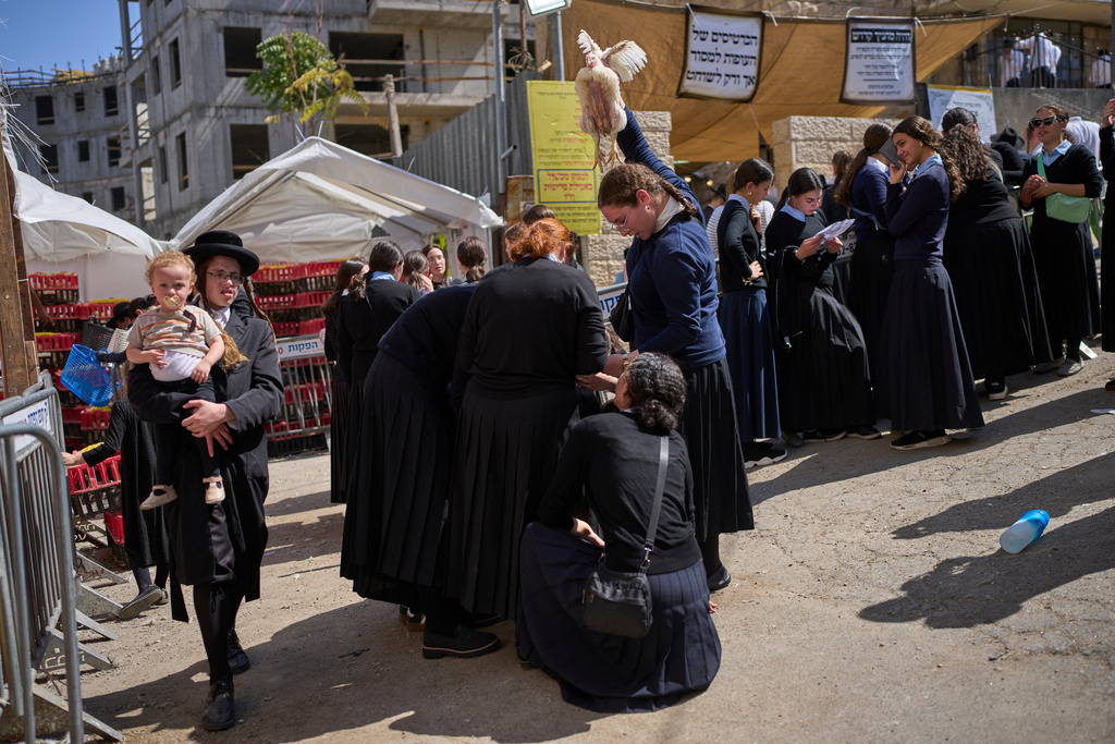 An ultra-Orthodox Jewish woman swings a chicken over head in Jerusalem, Monday, Sept. 29, 2025, as part of the Kaparot ritual before the Jewish holiday of Yom Kippur. (AP Photo/Ohad Zwigenberg)