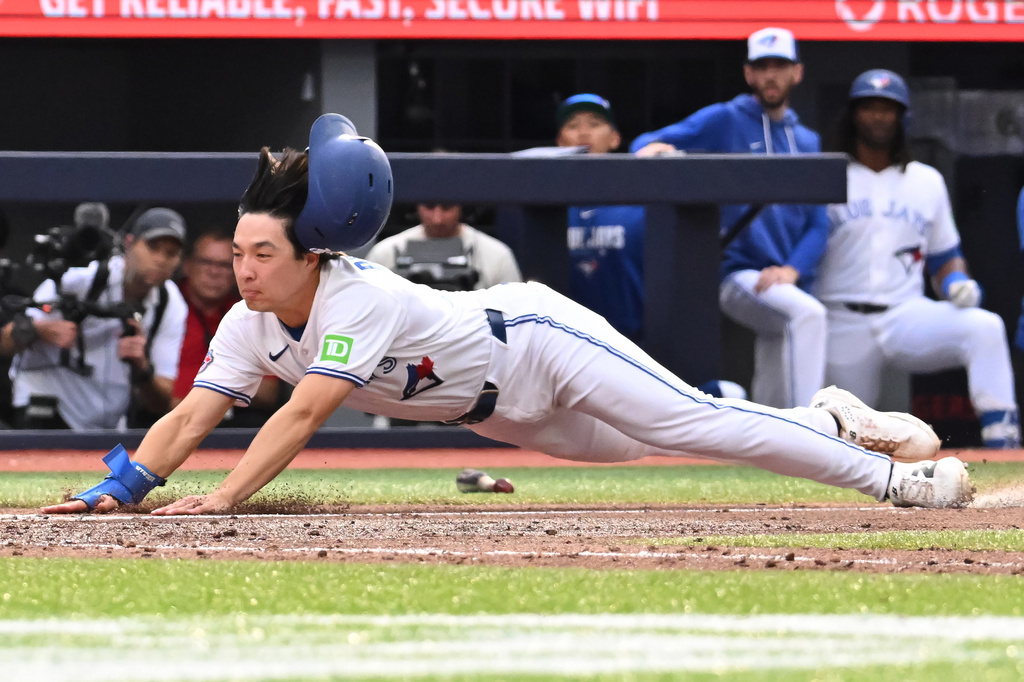 Toronto Blue Jays' Brett Bateman, right, scores on a wild pitch during the fifth inning of a baseball game in Toronto, Saturday, Aug. 29, 2026. (Jon Blacker/The Canadian Press via AP)