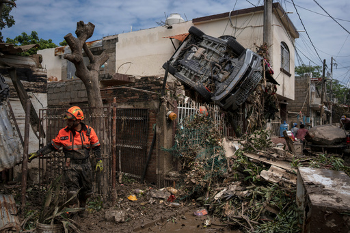 A rescue worker, part of the volunteer brigade known as the Topos, works near a car hanging over a fence by a damaged house in Poza Rica, Mexico, Monday, Oct. 13, 2025, after torrential rains. (AP Photo/Felix Marquez) A rescue worker, part of the volunteer brigade known as the Topos, works near a car hanging over a fence by a damaged house in Poza Rica, Mexico, Monday, Oct. 13, 2025, after torrential rains. (AP Photo/Felix Marquez)