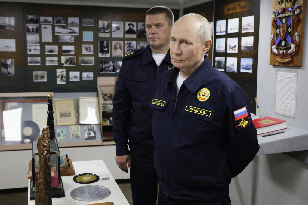 Russian President Vladimir Putin, right, and Admiral Viktor Liina listen to a navy officer during a visit to the Varyag missile cruiser of the Pacific Fleet to watch a military exercise near Yuzhno-Sakhalinsk, on Sakhalin Island, Russia, Wednesday, Aug. 12, 2026. (Gavriil Grigorov, Sputnik, Kremlin Pool Photo via AP)