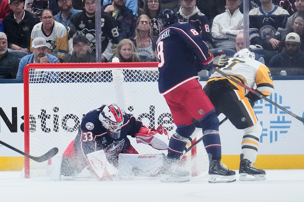 Columbus Blue Jackets goalie Cam Talbot (33) blocks a shot by Pittsburgh Penguins center Sidney Crosby (87), next to Zach Werenski (8), in overtime of an NHL hockey game in Columbus, Ohio, Friday, Oct. 9, 2026. (AP Photo/Sue Ogrocki)