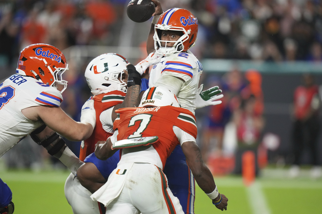 Florida quarterback DJ Lagway (2) is pressured by Miami defensive lineman Akheem Mesidor, second from left, and defensive back Zechariah Poyser, right, during the first half of an NCAA college football game, Saturday, Sept. 20, 2025, in Miami Gardens, Fla. (AP Photo/Lynne Sladky)