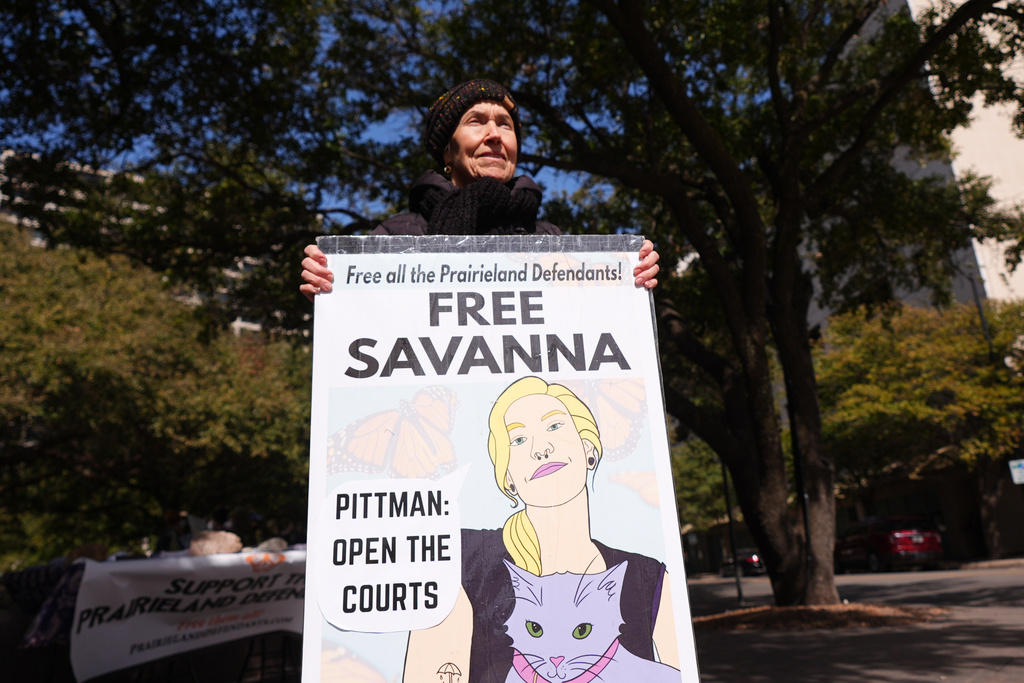 Susan Oakey holds a sign across the street from the Eldon B. Mahon U.S. Courthouse during a trial for nine people connected to a 2025 shooting outside an ICE detention facility Tuesday, Feb. 24, 2026, in Fort Worth, Texas. (AP Photo/LM Otero)