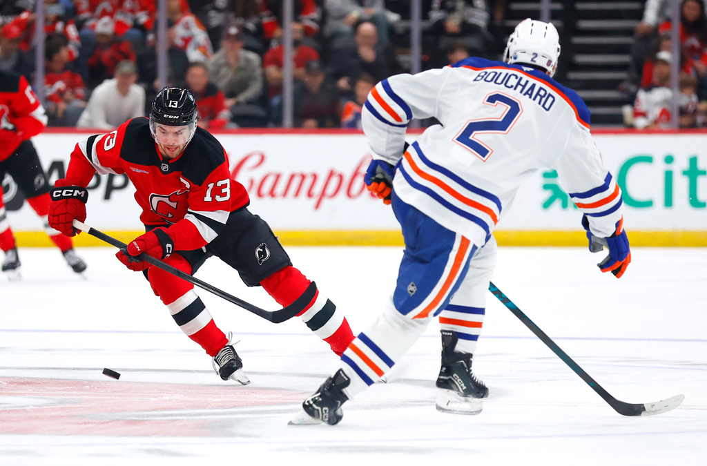 CORRECTS YEAR TO 2025, NOT 2024 - New Jersey Devils center Nico Hischier (13) plays the puck against Edmonton Oilers defenseman Evan Bouchard (2) during the second period of an NHL hockey game, Saturday, Oct. 18, 2025, in Newark, N.J. (AP Photo/Noah K. Murray)