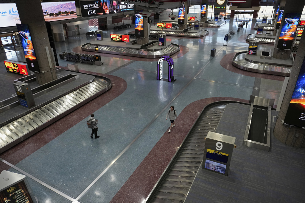 People walk through Harry Reid International Airport, Friday, Aug. 29, 2025, in Las Vegas. (AP Photo/John Locher)