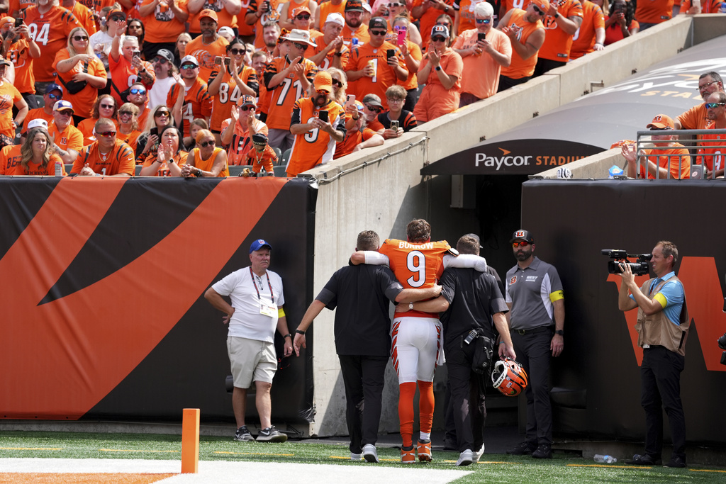 Cincinnati Bengals quarterback Joe Burrow, center, is helped off the field after suffering an injury during the second quarter of an NFL football game against the Jacksonville Jaguars, Sunday, Sept. 14, 2025, in Cincinnati. (AP Photo/Kareem Elgazzar)