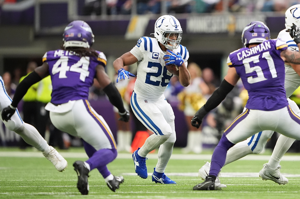 Indianapolis Colts running back Jonathan Taylor (28) runs against Minnesota Vikings safety Josh Metellus (44) and linebacker Blake Cashman (51) during the second half of an NFL football game in Minneapolis, Sunday, Oct. 25, 2026. (AP Photo/Ellen Schmidt)