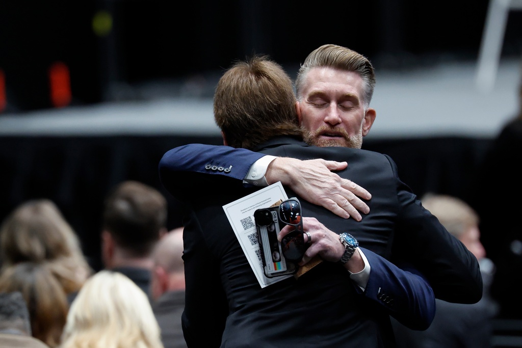 ESPN's Marty Smith, right, hugs a person at the NASCAR Plane Crash Memorial memorial in Charlotte, N.C., Friday, Jan. 16, 2026. (AP Photo/Nell Redmond)