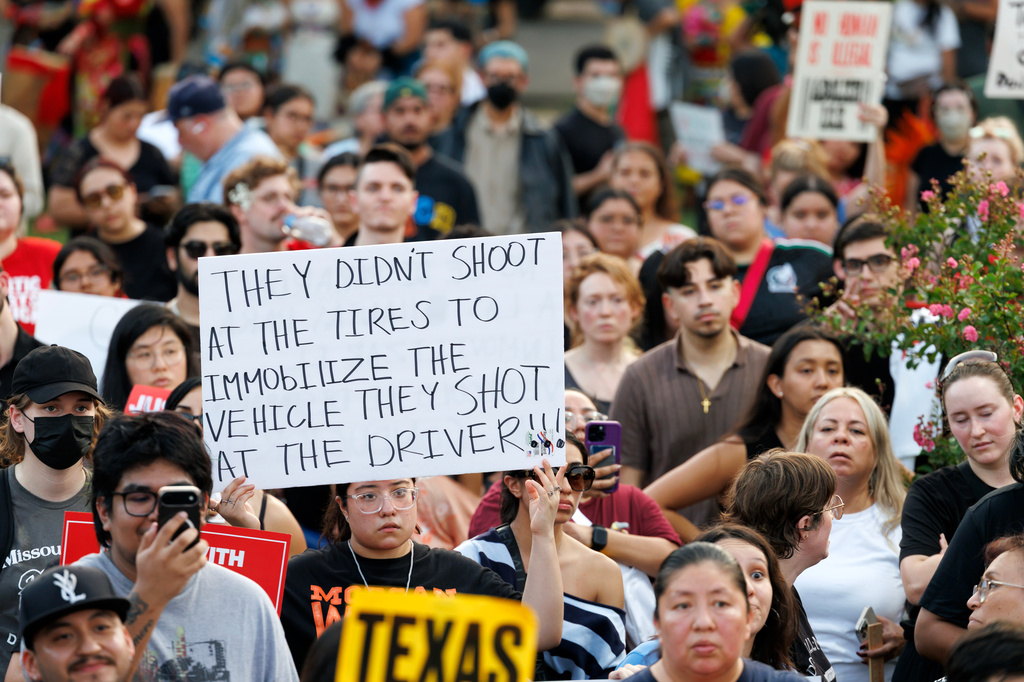 A woman holds up a sign during a vigil for Lorenzo Salgado Araujo, a Mexican national fatally shot by a federal immigration agent a day prior, Wednesday, July 8, 2026, in Houston. (AP Photo/Mark Felix)
