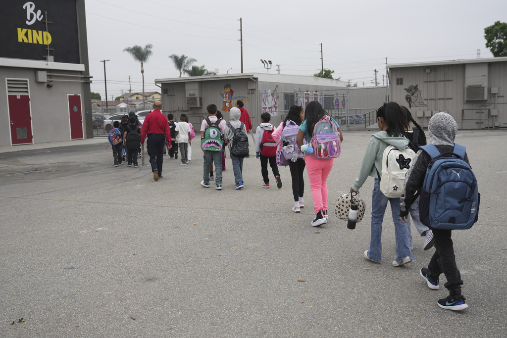 Teachers walk with students on the first day of school Thursday, Aug. 14, 2025, in Los Angeles. (AP Photo/Marcio Jose Sanchez)