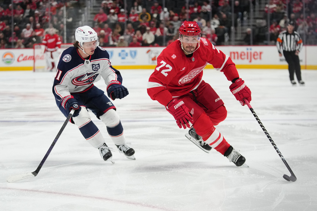 Detroit Red Wings defenseman Justin Faulk (72) protects the puck from Columbus Blue Jackets center Kent Johnson (91) in the second period of an NHL hockey game Tuesday, April 7, 2026, in Detroit. (AP Photo/Paul Sancya)