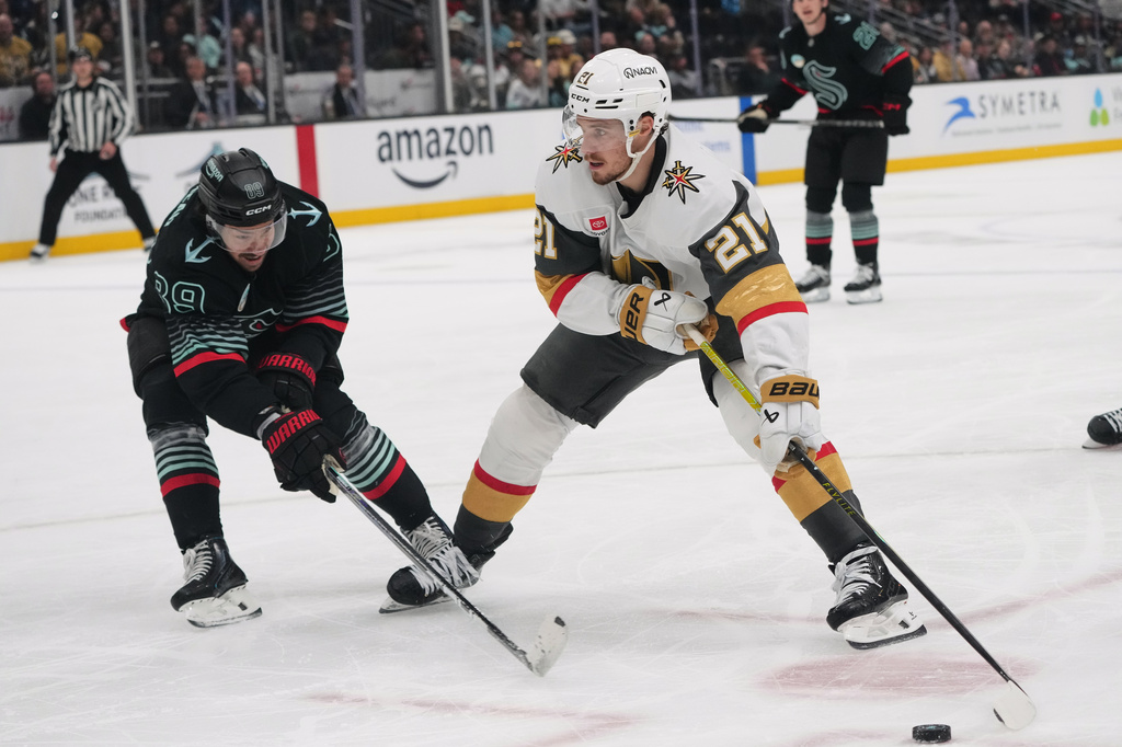 Vegas Golden Knights center Brett Howden (21) moves the puck against Seattle Kraken center Frederick Gaudreau, left, during the second period of an NHL hockey game Thursday, April 9, 2026, in Seattle. (AP Photo/Lindsey Wasson)