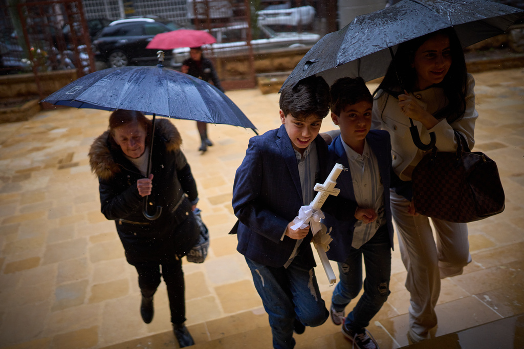 Worshippers shelter from the rain under umbrellas as they arrive at a church to attend a Palm Sunday Mass in Beirut, Lebanon, Sunday, March 29, 2026. (AP Photo/Emilio Morenatti)