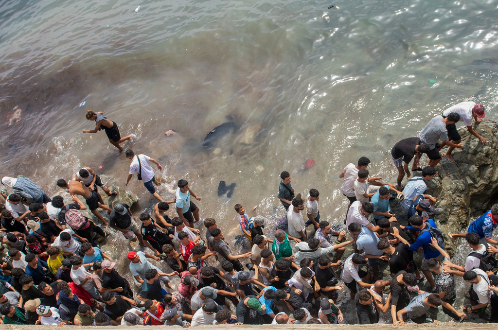 People walk on a beach as they attempt to cross from the Moroccan northern town of Fnideq to the Spanish enclave of Ceuta, Friday, July 31, 2026. (AP Photo)