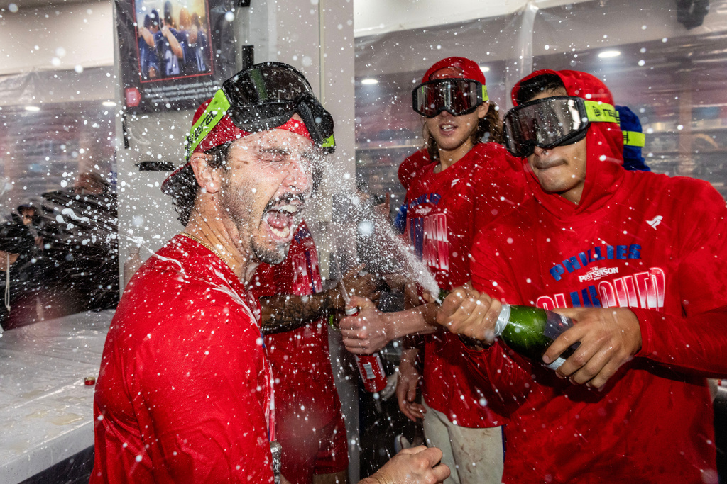 Philadelphia Phillies catcher Garrett Stubbs, left, is doused by teammates during a celebration in the clubhouse after the team clinched a Wild Card slot in the postseason by defeating the Tampa Bay Rays in a baseball game Sunday, Sept. 27, 2026, in Philadelphia. (AP Photo/Laurence Kesterson)