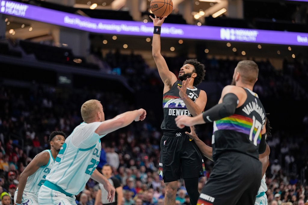 Denver Nuggets guard Jamal Murray, second from right, shoots a jump shot over Charlotte Hornets center Mason Plumlee, front left, during the first half of an NBA basketball game in Charlotte, N.C., Sunday, Dec. 7, 2025. (AP Photo/Jim Dedmon)