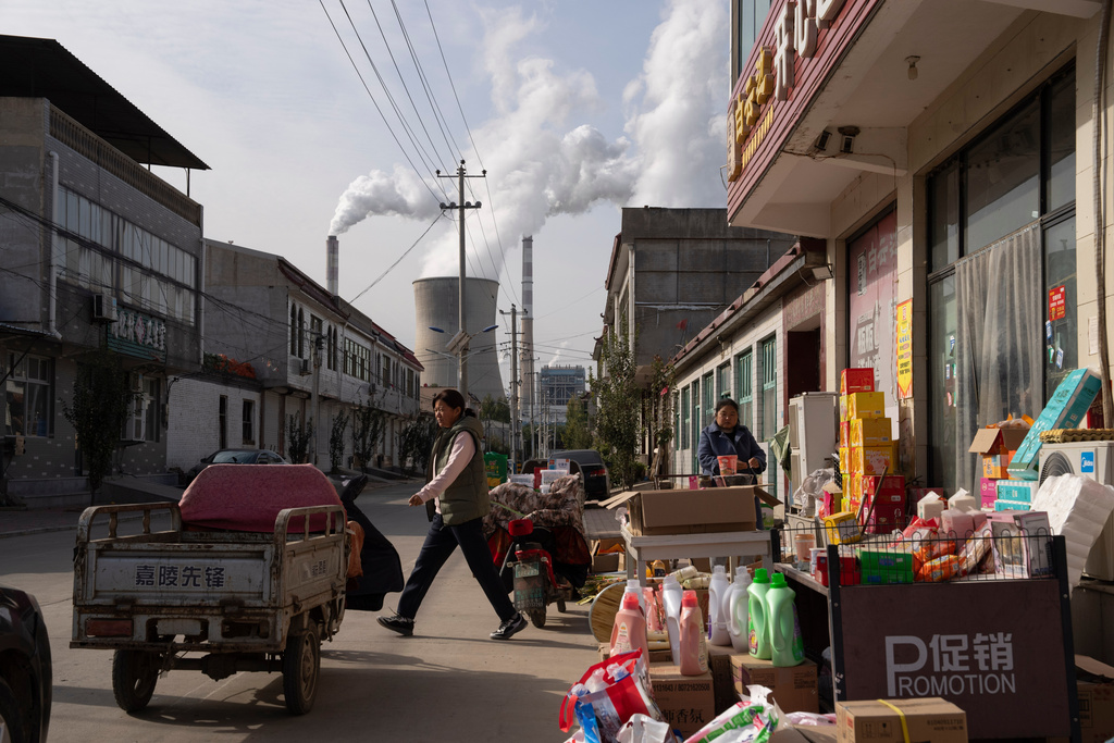 FILE- Guohua Power Station, a coal-fired power plant, operates as people sell items on a street in Dingzhou, Baoding, in northern China's Hebei province, Friday, Nov. 10, 2023. (AP Photo/Ng Han Guan, File)