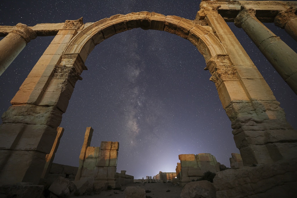 The entrance to the Roman Theater's precinct, part of the ruins of the ancient city of Palmyra, is seen under a star-studded sky in Syria, late Wednesday, Aug. 27, 2025. (AP Photo/Ghaith Alsayed)