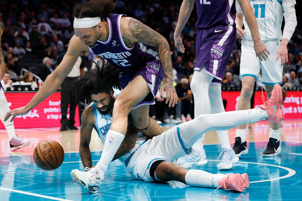 Sacramento Kings guard Devin Carter (22) falls over Charlotte Hornets guard Coby White for the ball during the first half of an NBA basketball game in Charlotte, N.C., Tuesday, March 24, 2026. (AP Photo/Nell Redmond)