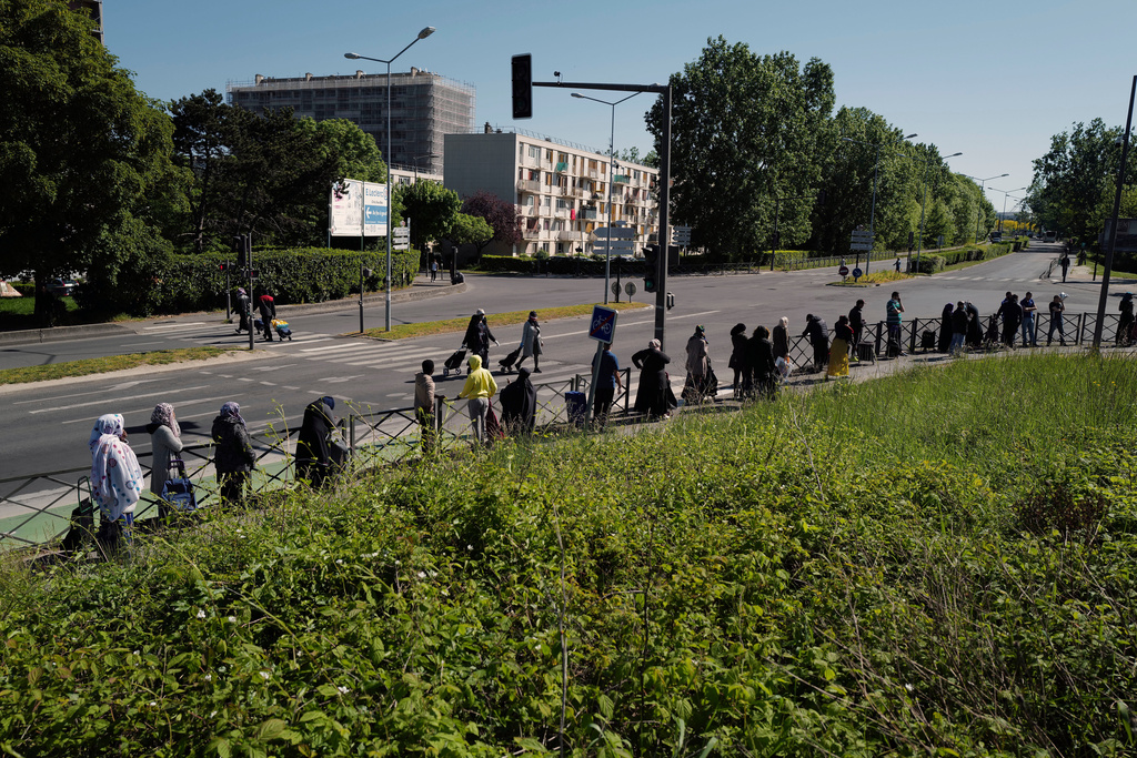 FILE - Residents line up during a distribution to collect soap, vegetables, fruits and other staples distributed by volunteers from community organizations of ACLEFEU in Clichy-sous-Bois, north suburb of Paris, Wednesday, April 22, 2020 as a nationwide confinement continues to counter the COVID-19. (AP Photo/Francois Mori, File)