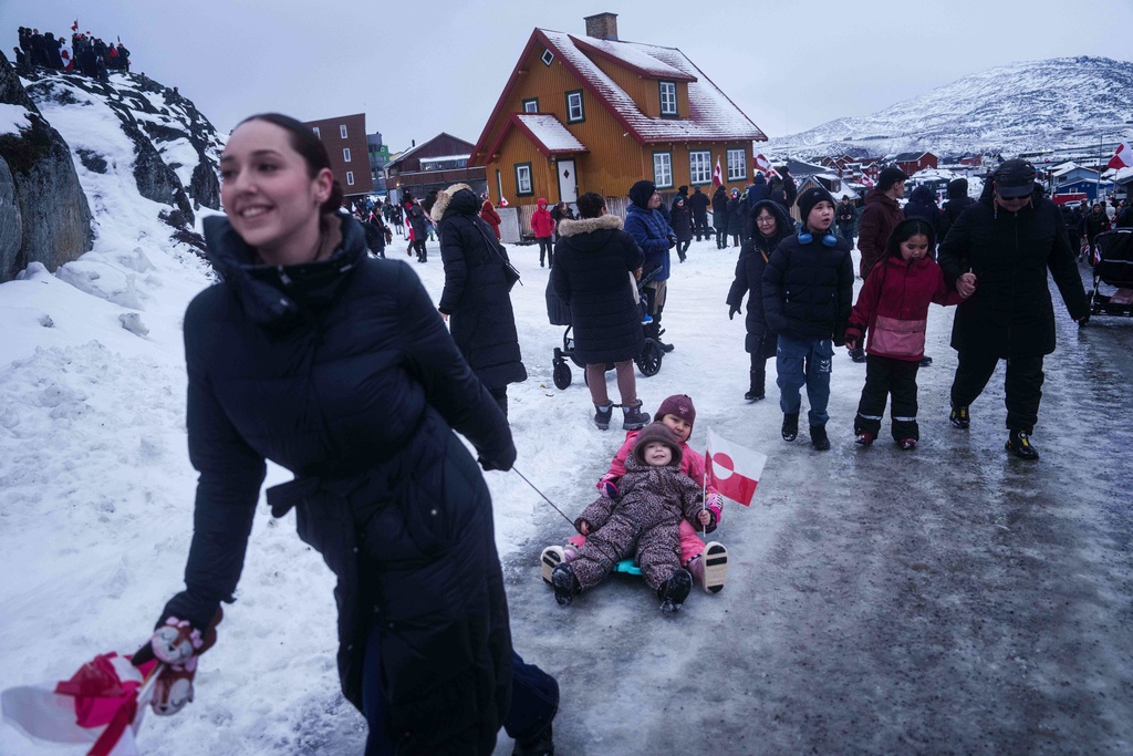 A woman pulls her children on a sled during a protest against Trump's policy towards Greenland in front of the US consulate in Nuuk, Greenland, Saturday, Jan. 17, 2026. (AP Photo/Evgeniy Maloletka)
