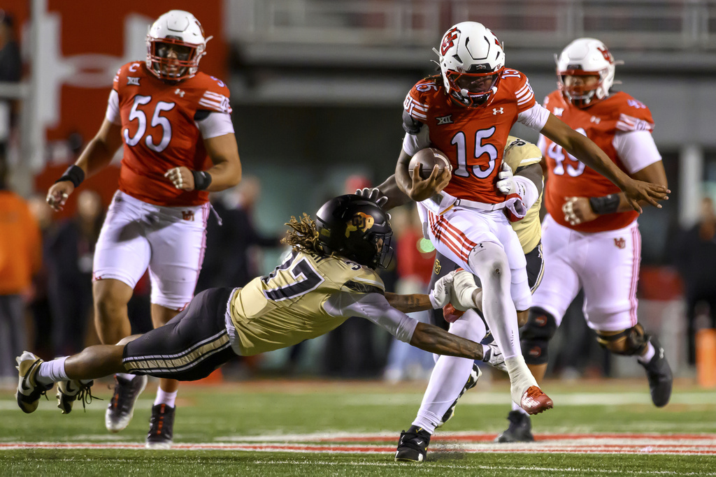 Utah quarterback Byrd Ficklin (15) jumps to avoid a tackle by Colorado linebacker Martavius French (37) during the first half an NCAA college football game, Saturday, Oct. 25, 2025, in Salt Lake City, Utah. (AP Photo/Tyler Tate)